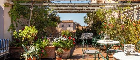 Un espace patio aménagé avec des meubles d’extérieur, des plantes en pot et une vue sur les bâtiments en arrière-plan.