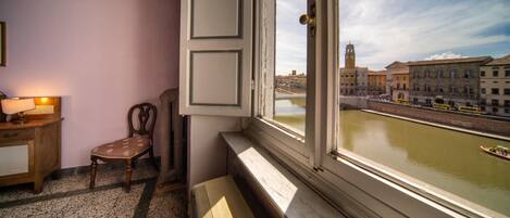 Una habitación con vistas al río, una silla, una lámpara y un banco junto a la ventana.