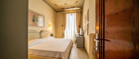 Una habitación de hotel con cama, escritorio, silla y armario.