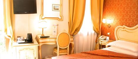 Una habitación de hotel con una cama, un escritorio con silla, un televisor, un teléfono y una lámpara.