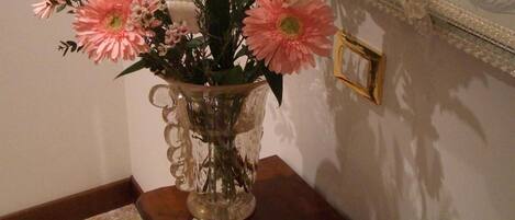 Una habitación con una mesa que sostiene un jarrón de flores y un libro abierto.