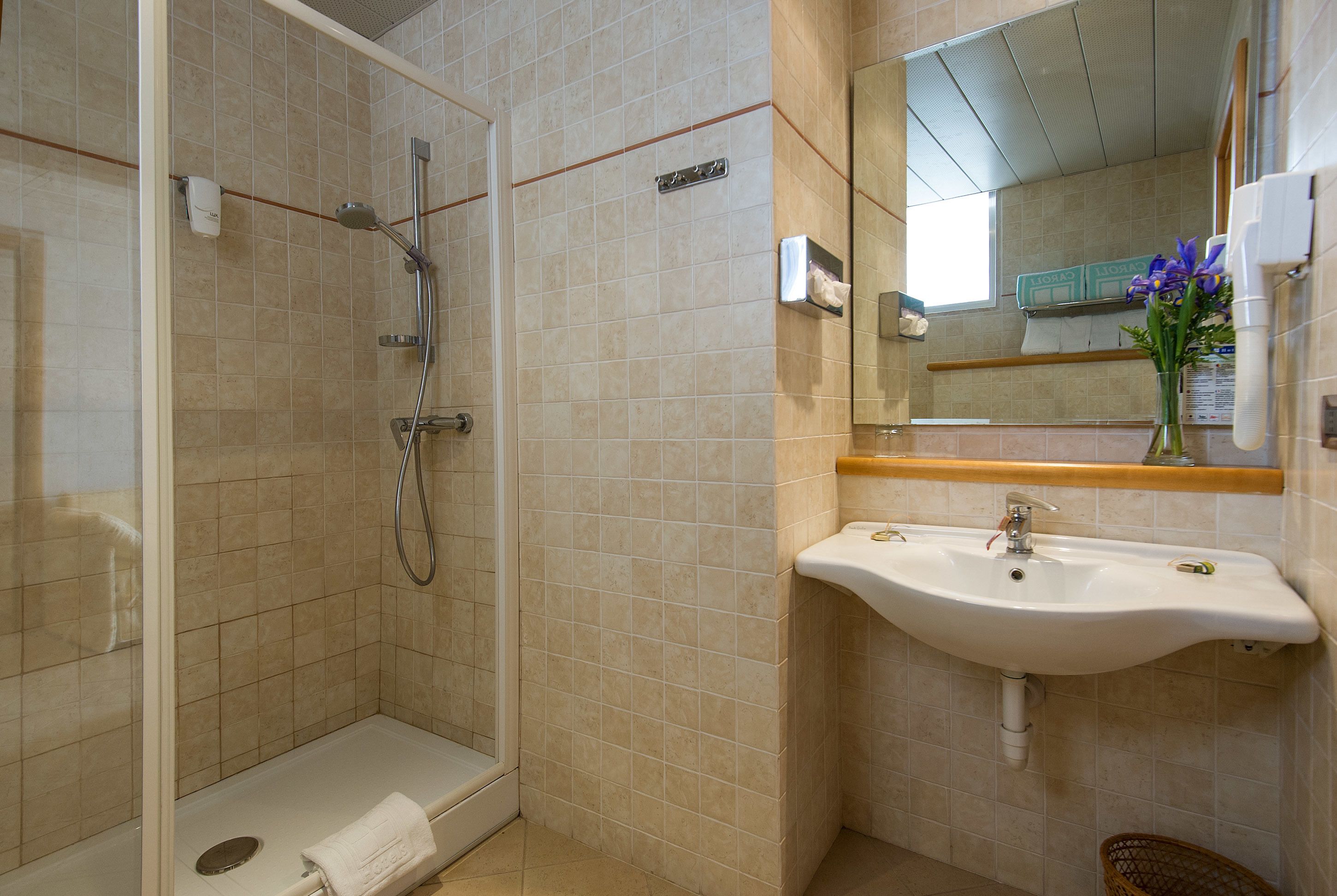 Une salle de bain avec une douche à parois de verre, un lavabo et un miroir.