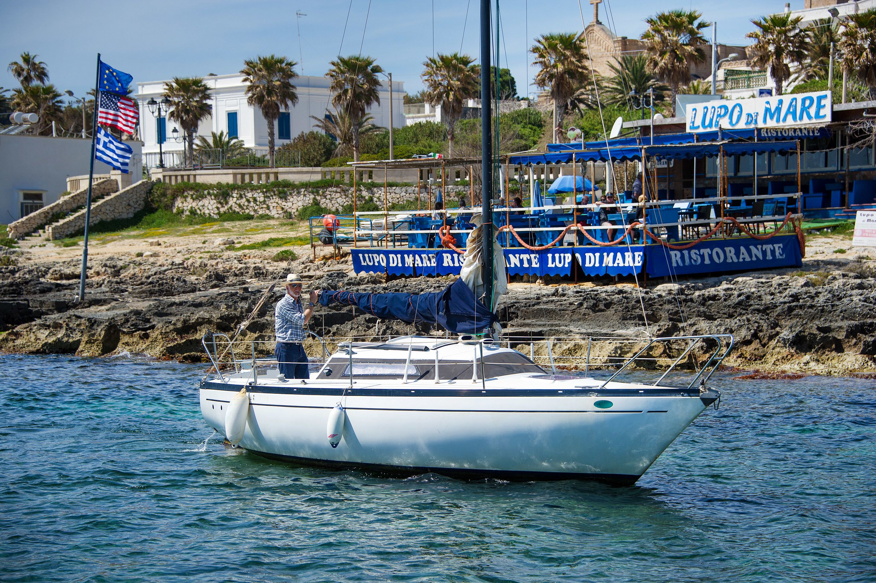 A boat docked near a waterfront restaurant named "LUPO DI MARE RISTORANTE LUPO DI MARE".