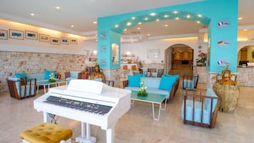 A spacious lobby with a piano, seating areas, and a bar.