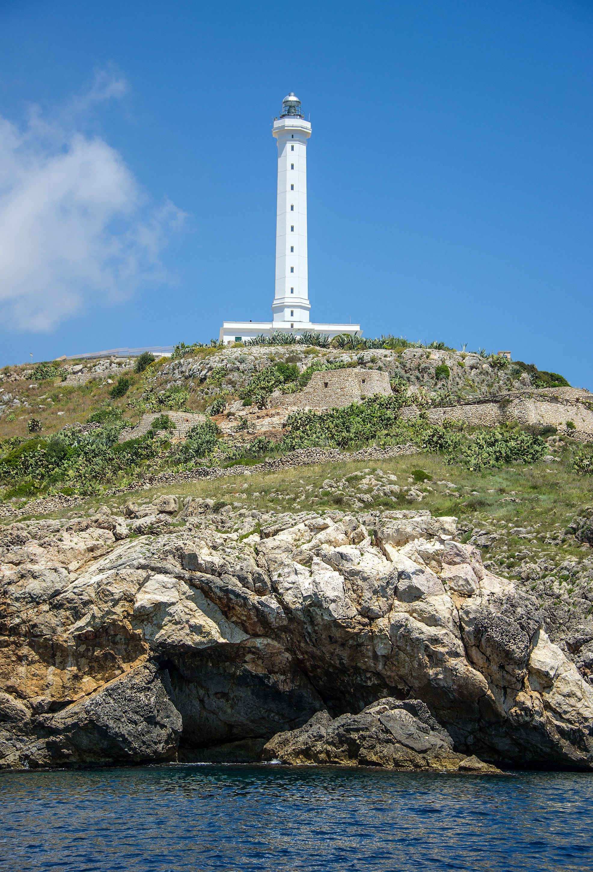 Un faro blanco sobre una colina rocosa bajo un cielo azul despejado.