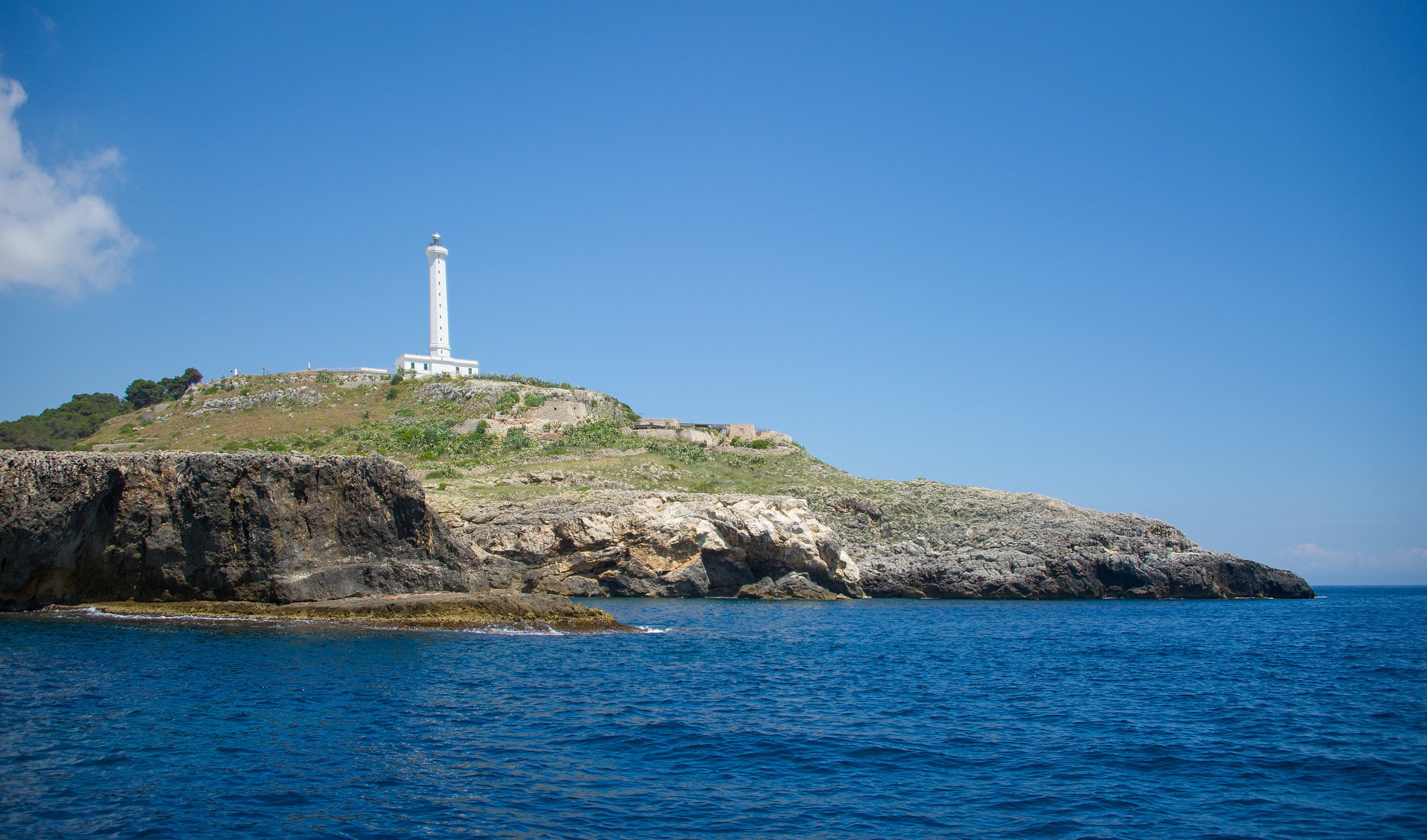 Ein Leuchtturm auf einer felsigen Insel mit klarem, blauem Wasser.