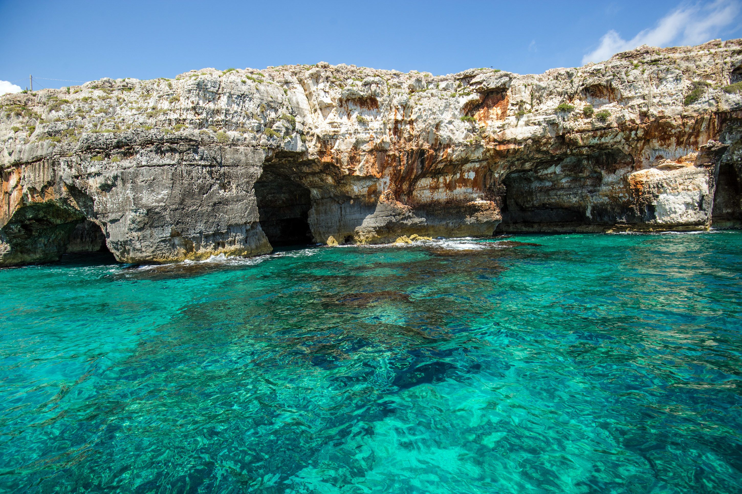 A coastal scene with clear turquoise water and rocky cliffs.
