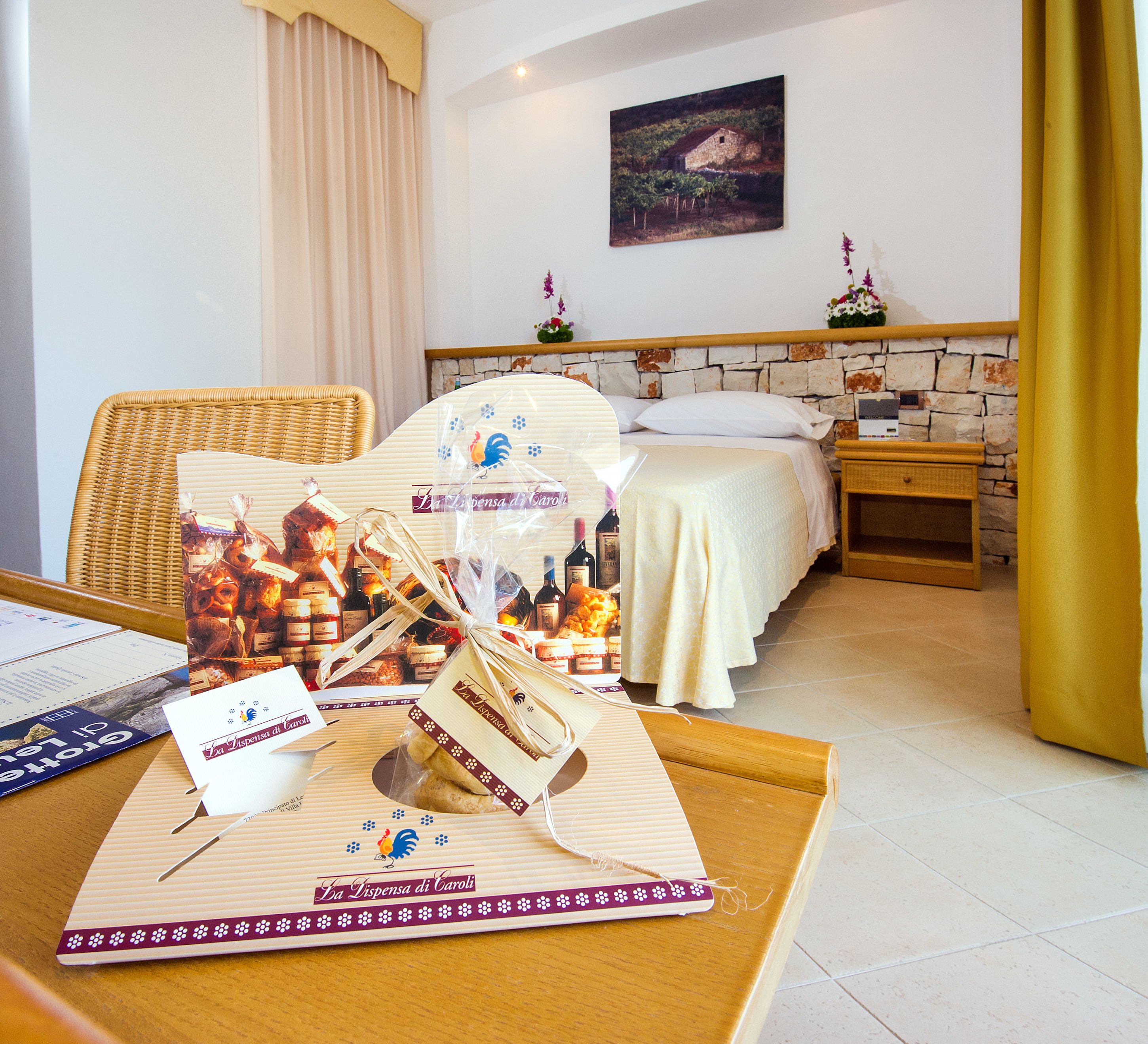 Une chambre d’hôtel avec un lit, une table en bois sur laquelle se trouve un menu, et un tableau accroché au mur.