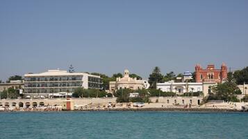 A coastal hotel with multiple buildings, a beach area, and a clear view of the sea.