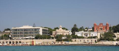 Un hotel costero con varias construcciones, zona de playa y vista despejada al mar.