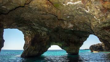 A natural rock formation with a clear view of the sea through an archway.