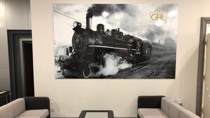 Una sala de estar moderna con dos sofás, una mesa de centro y una fotografía grande en blanco y negro de una locomotora de vapor en la pared.