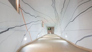 Un pasillo con pared de mármol que presenta patrones lineales y suelo de baldosas.