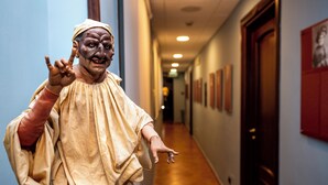 A person in a costume in a hallway with a wooden floor and framed pictures on the walls. - Hotel Neapolis (Naples)