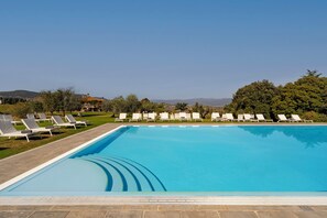 Una piscina al aire libre, sillones reclinables de piscina