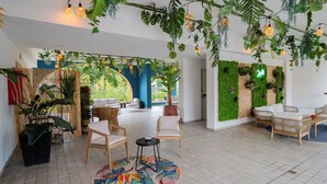 A spacious indoor area with a tiled floor, wicker furniture, and a variety of plants. - Bleis Hotel (Bologna)