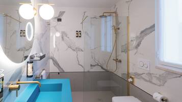 Un baño moderno con un lavamanos azul, ducha con cerramiento de vidrio y paredes de mármol.
