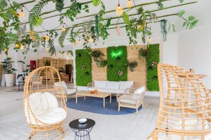 A modern living room with a white sofa, wicker chairs, and a coffee table. - Bleis Hotel (Bologna)