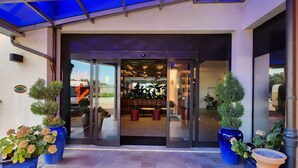 A hotel entrance with a covered patio, potted plants, and a view into the interior. - Bleis Hotel (Bologna)