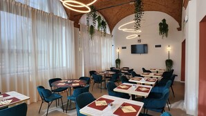 A restaurant with round tables, blue chairs, and hanging plants. - Bleis Hotel (Bologna)