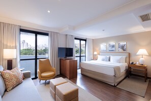 A hotel room with a large bed, a TV, a sofa, and a chair. - George V Alto De Pinheiros (São Paulo)