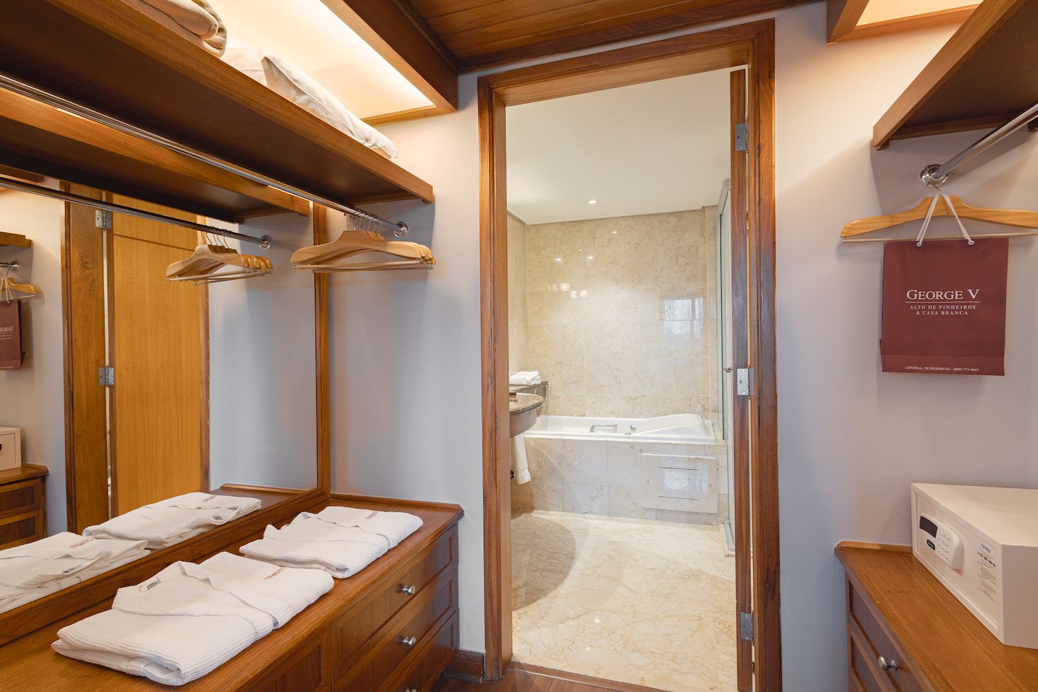 Een hotelbadkamer met een houten wastafelmeubel, een glazen douchecabine en een handdoekrek.