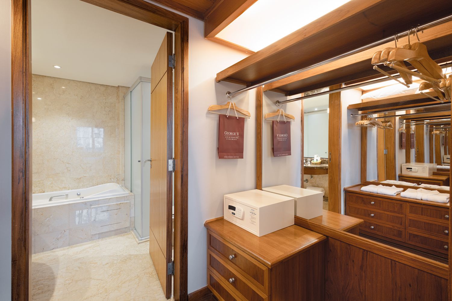 Une salle de bain d’hôtel avec une baignoire, un meuble-lavabo en bois et un grand miroir.