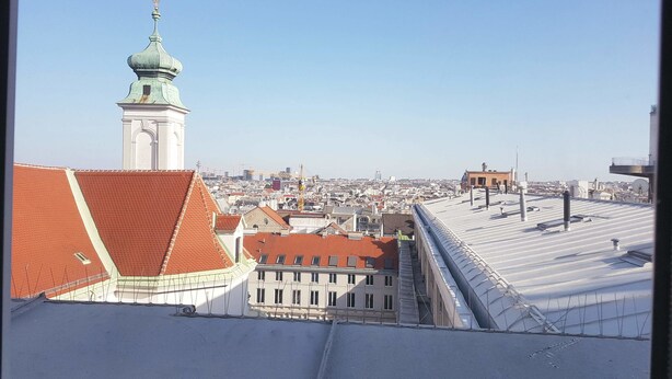 Eine Stadtansicht mit einem markanten Kirchturm und verschiedenen Dächern.