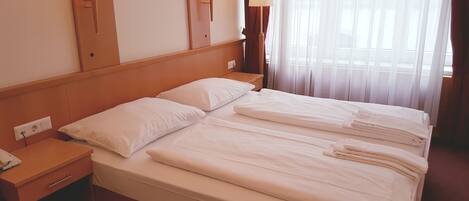 Habitación de hotel con una cama grande, dos mesitas de noche y dos lámparas de pared.