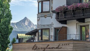 Ein Gebäude mit Balkon, im Hintergrund ein Berg, und ein Schild mit der Aufschrift 'Bergland'.