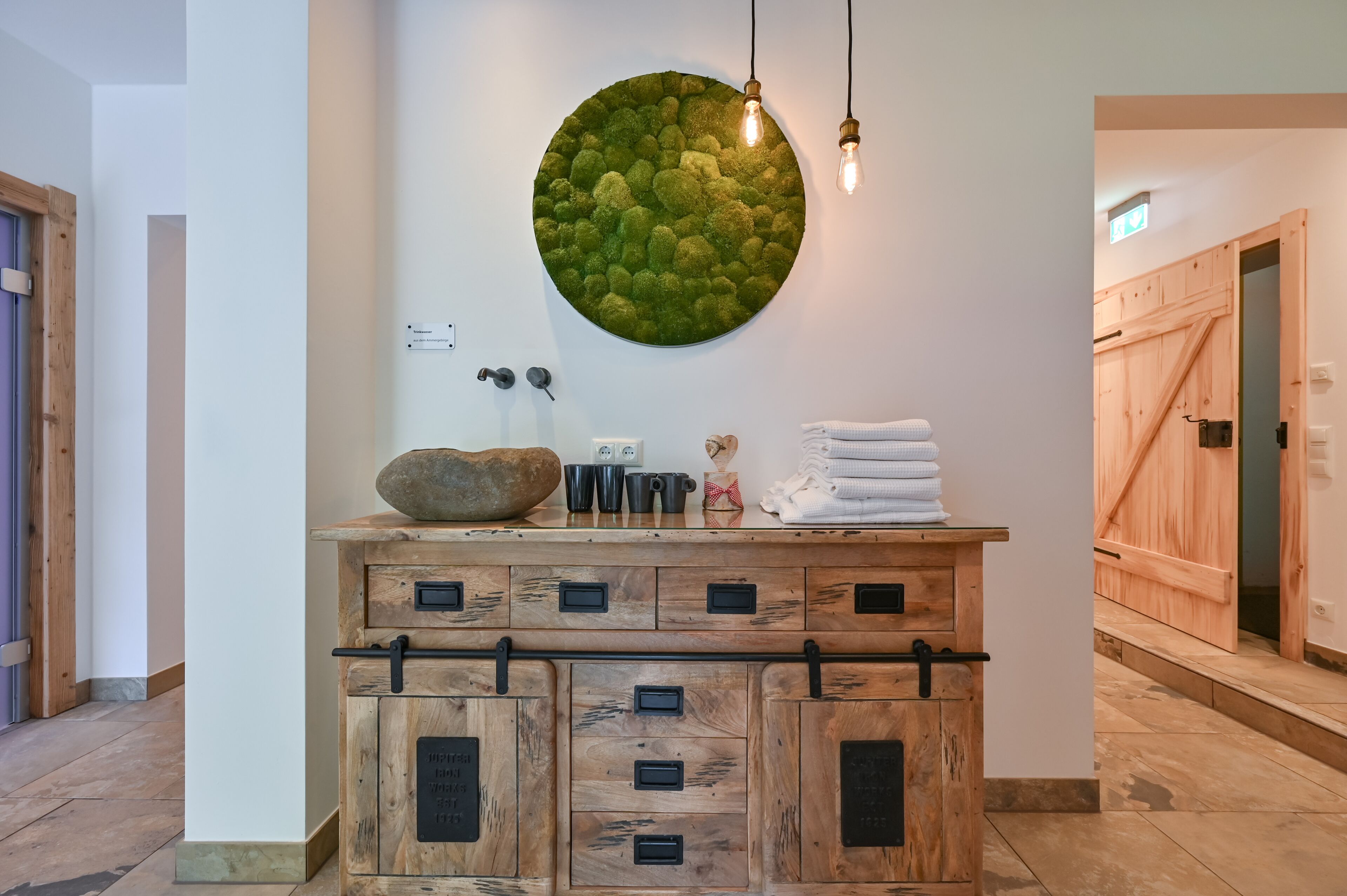 Een houten kast met meerdere lades en een ronde decoratie aan de muur erboven.