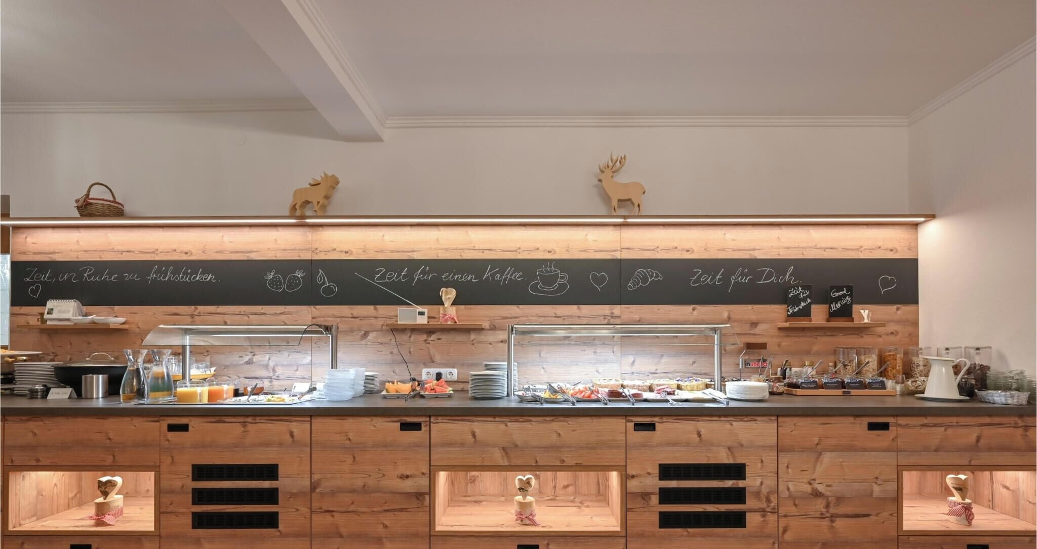 Een ontbijtbuffet met houten toonbanken, een prikbordmenu en diverse etenswaren.