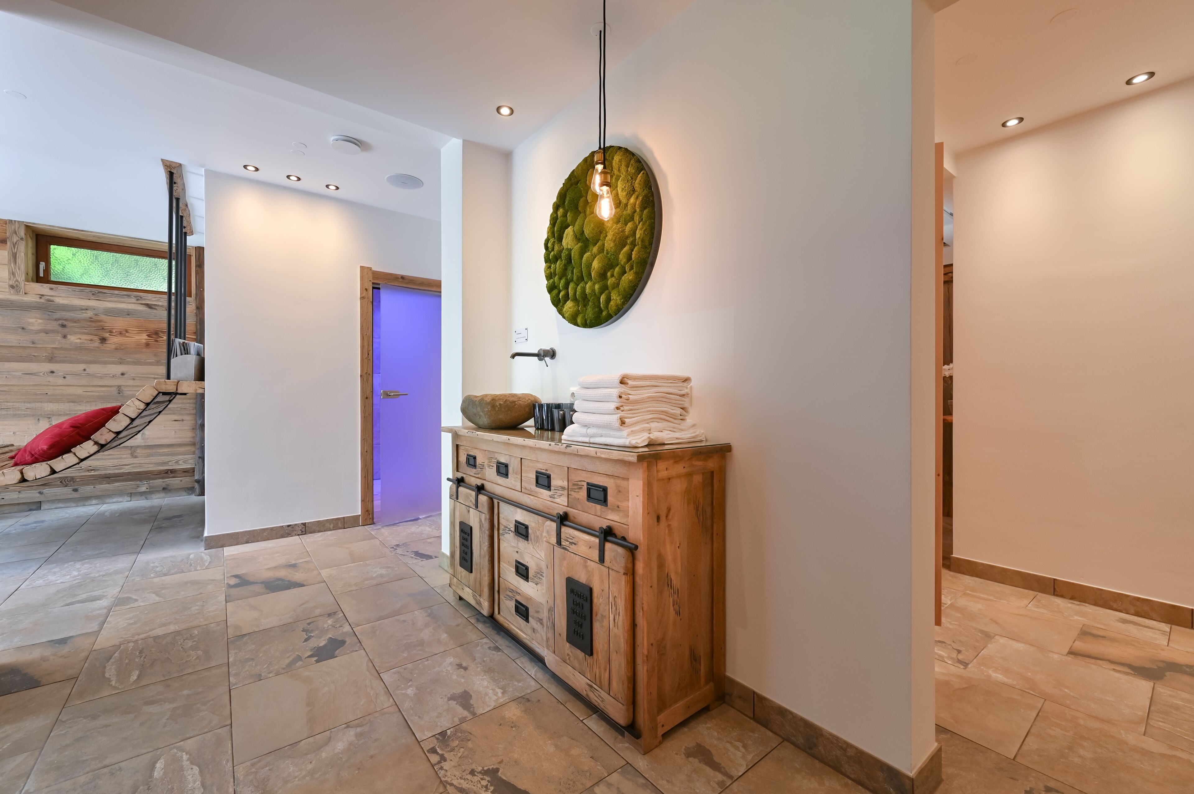 A modern interior with a wooden cabinet, a hanging light fixture, and a wooden wall with a window.