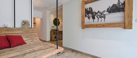 Un interior moderno con un banco de madera, una fotografía blanco y negro enmarcada en la pared y una cocina al fondo.