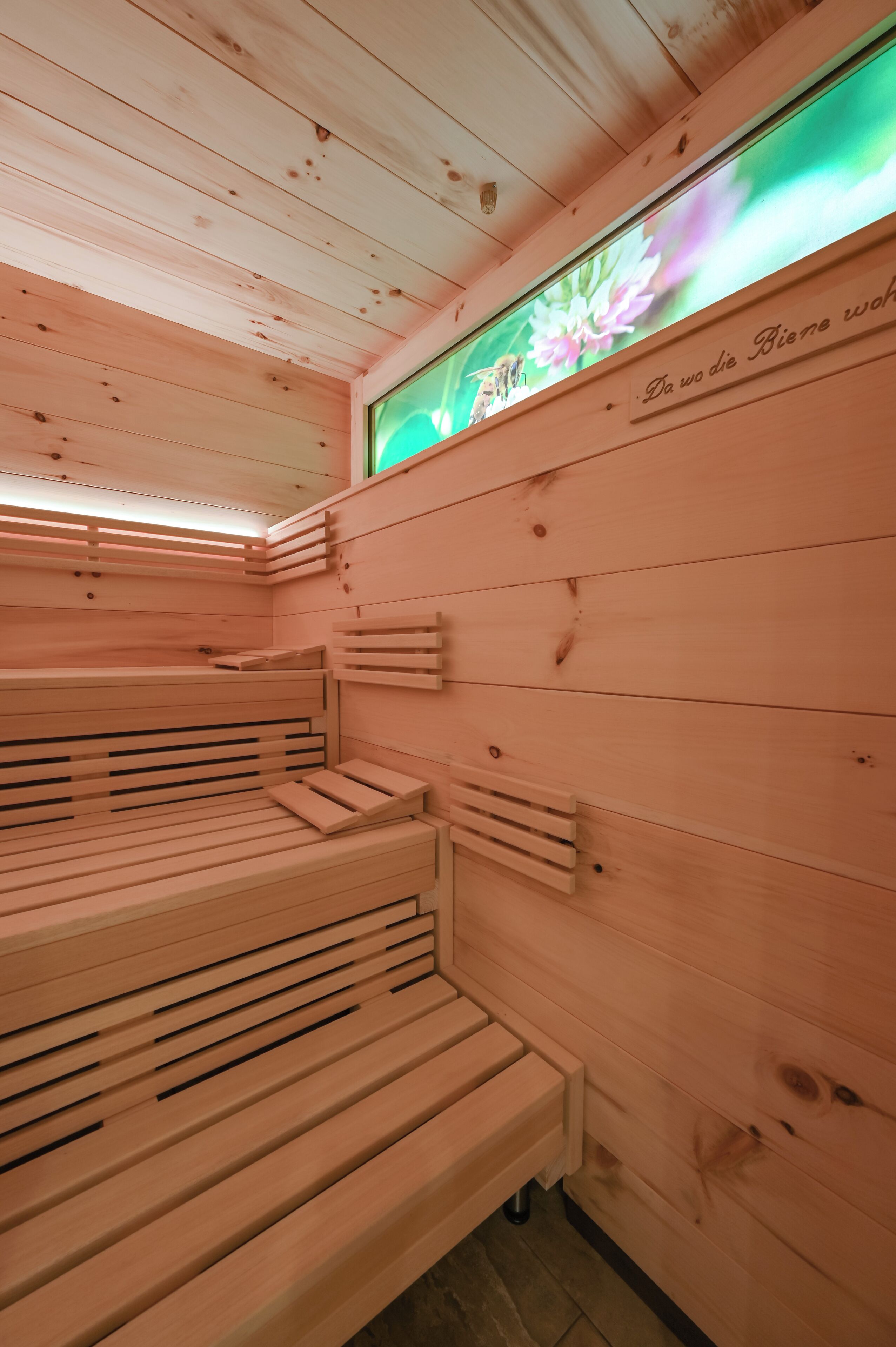 A sauna with wooden benches and a wall-mounted TV displaying flowers.