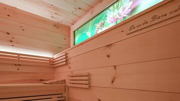 Een sauna met houten banken en een tv aan de muur waarop bloemen te zien zijn.