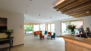 A spacious lobby with a reception desk, seating area, and large windows. - Vital Hotel Wiedemann (Fuessen)