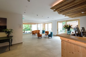 A spacious lobby with a reception desk, seating area, and large windows. - Vital Hotel Wiedemann (Fuessen)