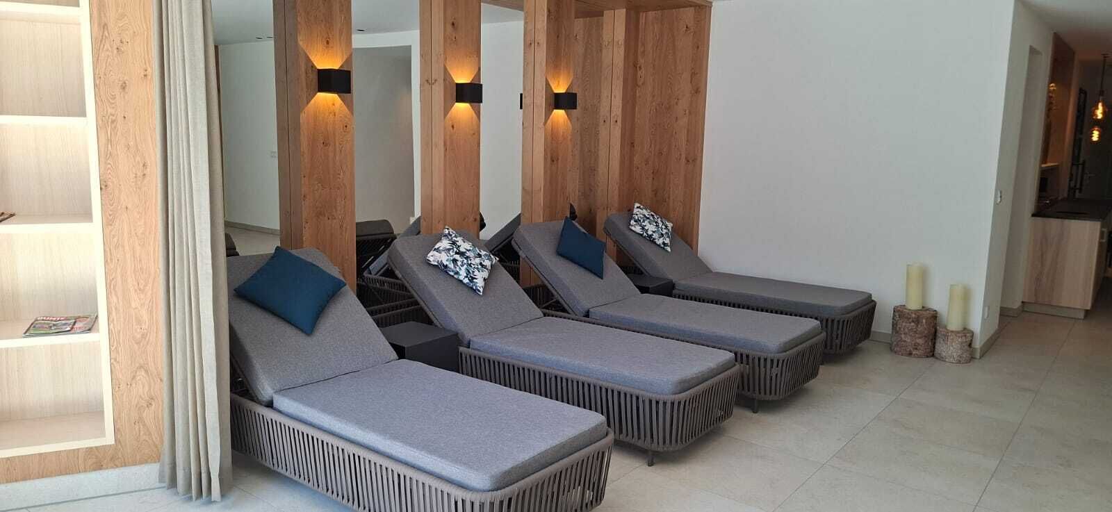 Una habitación con cuatro sillones, paneles de madera y una pequeña mesa con velas.
