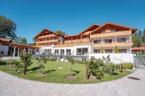 A multi-story hotel with a covered outdoor area and a landscaped garden. - Vital Hotel Wiedemann (Fuessen)