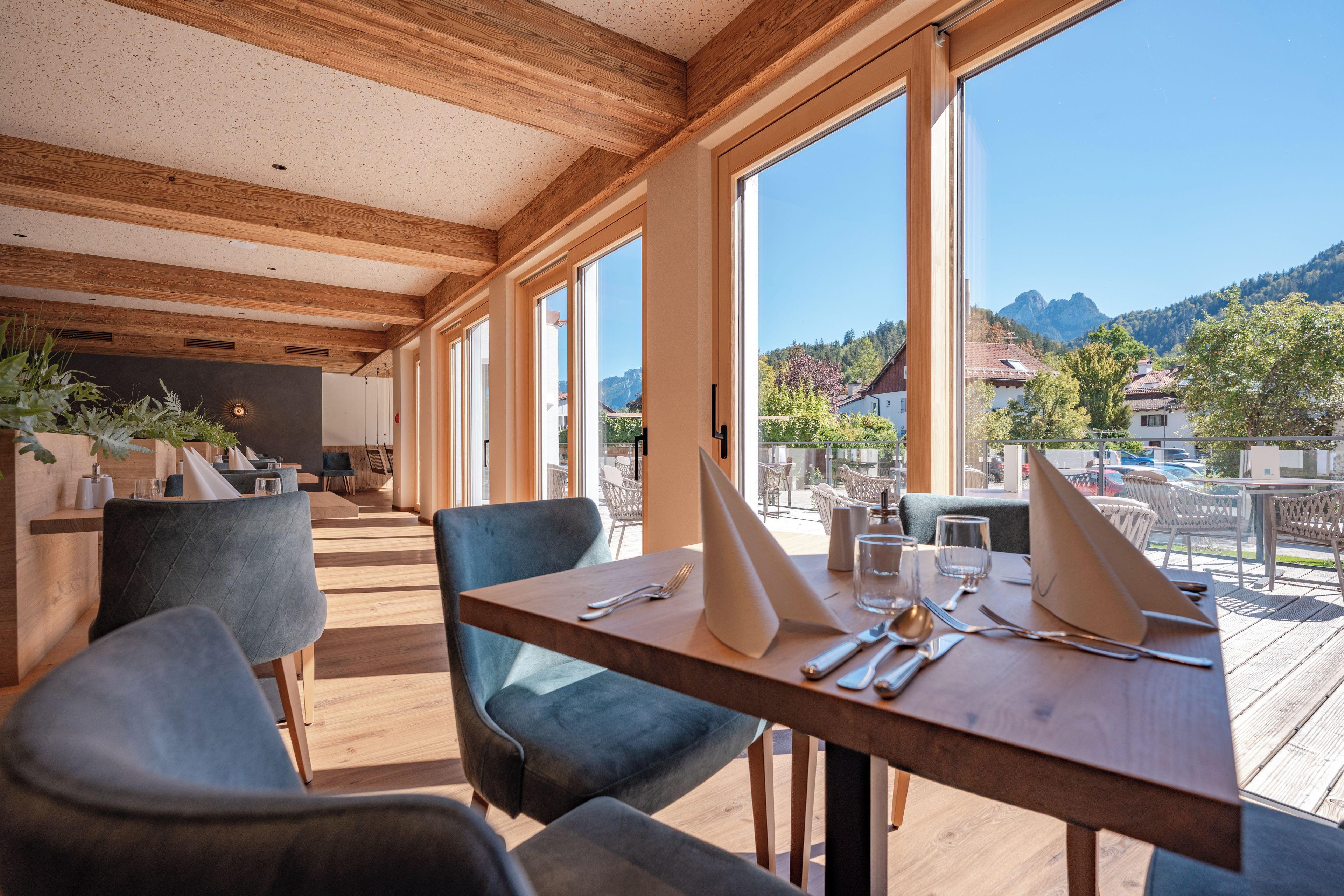 Een restaurant met houten balken in het plafond, grote ramen en uitzicht op bergen.