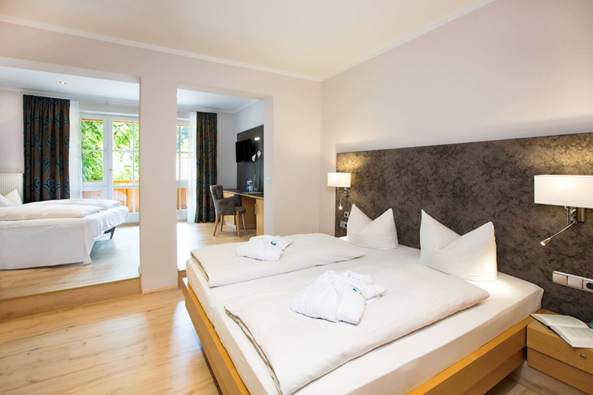 A hotel room with two beds, a desk, and a chair.