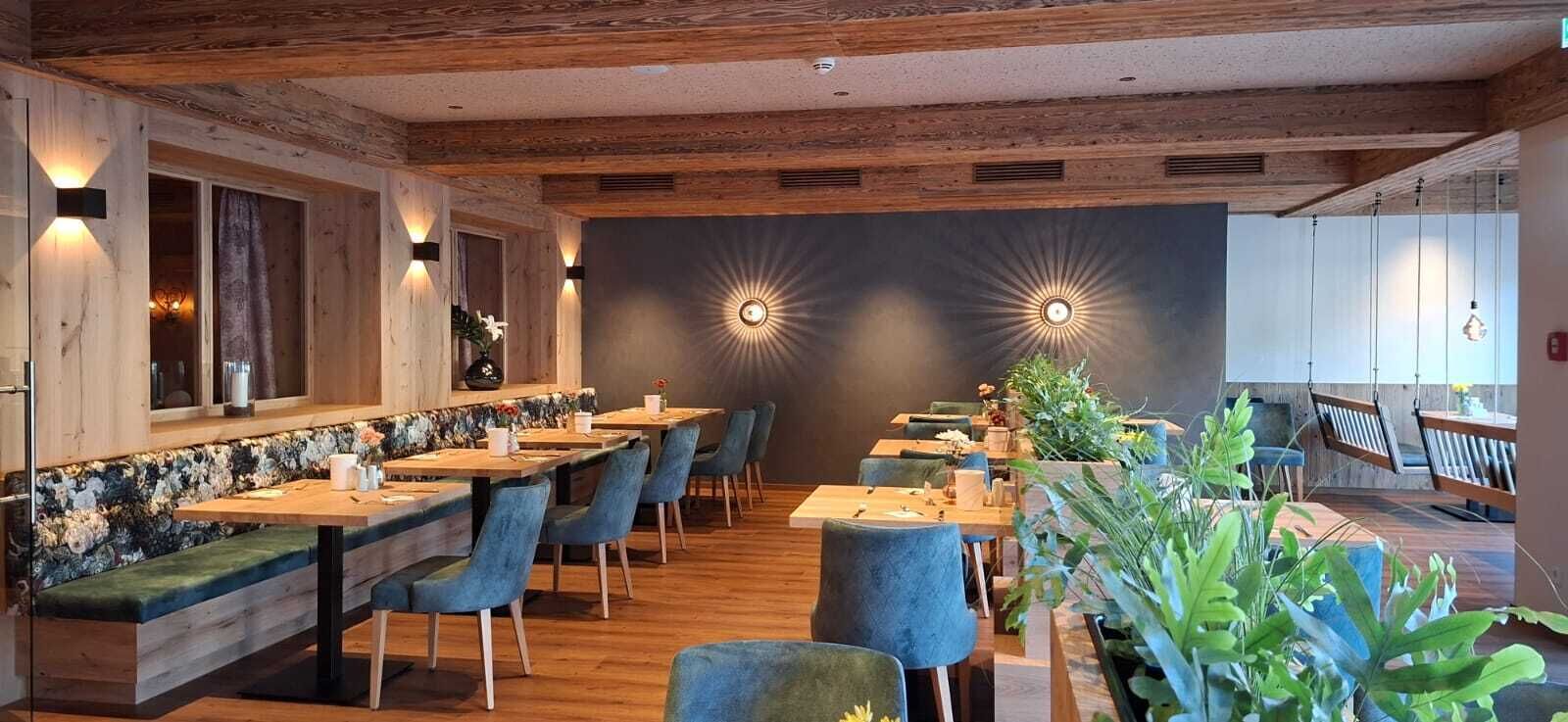 Un ristorante con travi in legno, sedie rivestite di blu e un lungo bancone con zoccolo floreale.