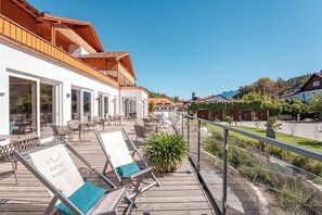 Eine Holzterrasse mit Liegestühlen und einem Schild, auf dem 'Kleine Auszeit' steht.