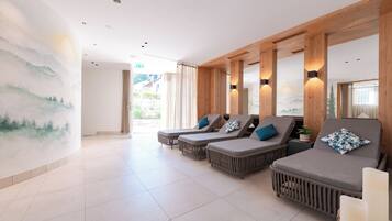 A spa area with three loungers, a large mural, and a view of the outdoors.