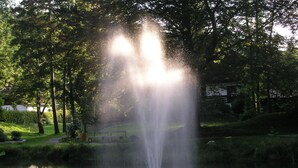 A fountain in a park with a bench nearby. - Vital Hotel Wiedemann (Fuessen)