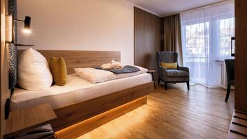 Habitación de hotel moderna con una cama de madera, una silla y vistas al exterior.