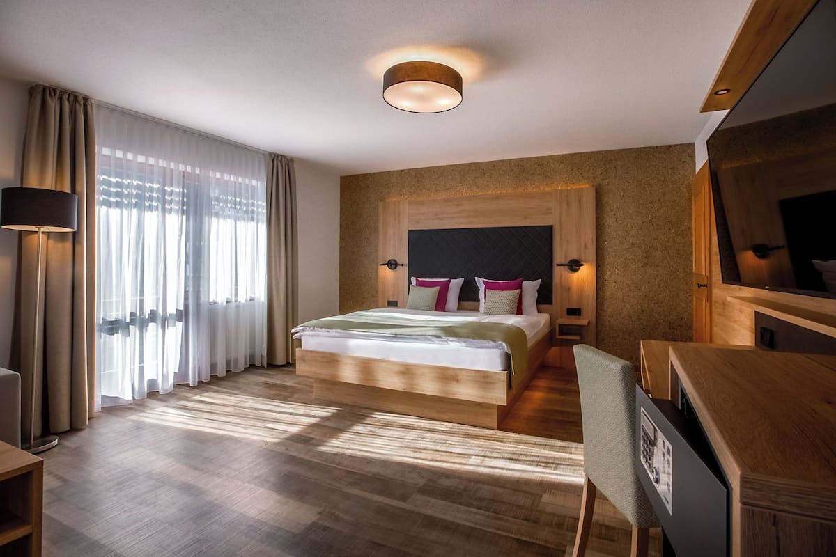 Une chambre d’hôtel avec un lit, des tables de chevet, un bureau et un grand miroir.