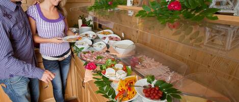 A buffet setup with various food items and a decorative arrangement of flowers and leaves.