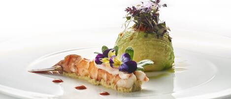 A plate with a salmon tartare and a mound of mashed potatoes topped with greens and flowers.